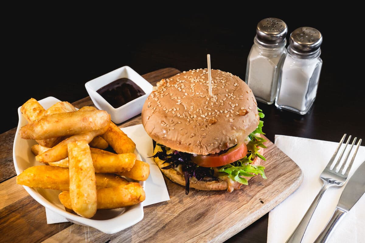 A burger served with a bowl of chips