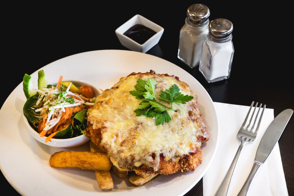 A chicken parmigiana with chips and salad